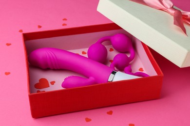 Gift box with sex toys on pink background, closeup