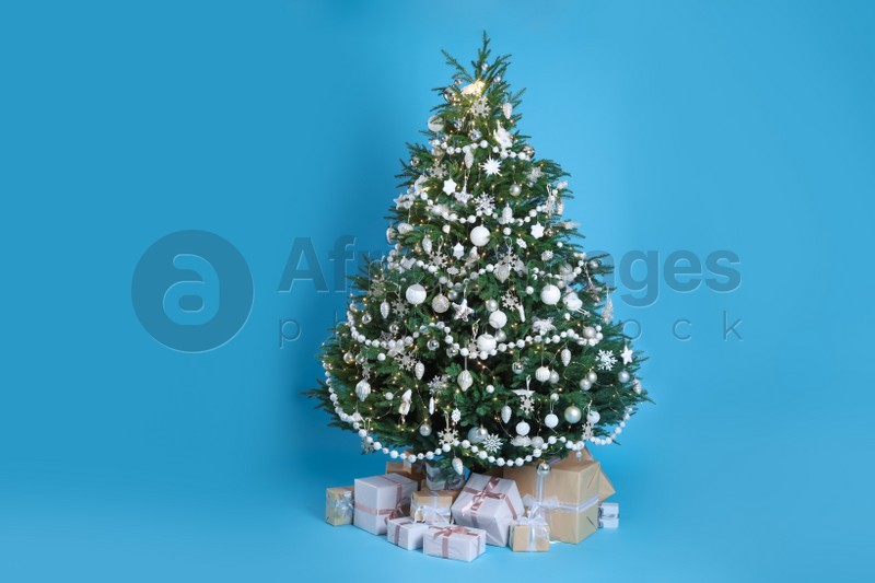 Beautiful Christmas tree and gift boxes on light blue background