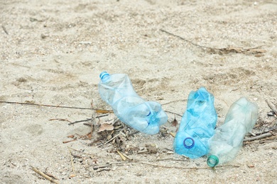 Used plastic bottles on beach, space for text. Recycling problem