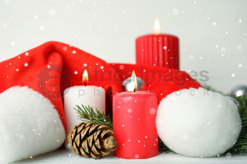 Photo of Snow falling on burning candles and festive decor against light background. Christmas eve
