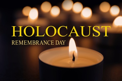 Image of International Holocaust Remembrance Day. Burning candle on table in darkness, closeup