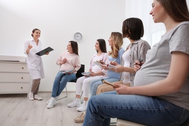 Group of pregnant women with doctor at courses for expectant mothers indoors