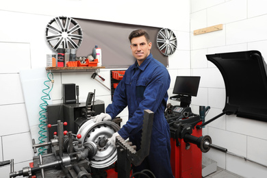 Man working with car disk lathe machine at tire service