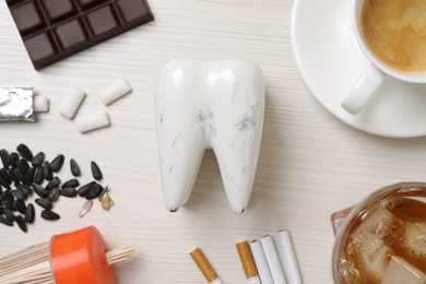 Photo of Flat lay composition with damaged tooth model and unhealthy food on white wooden table