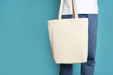 Man with cotton shopping eco bag on color background. Mockup for design