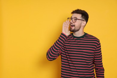 Photo of Handsome man in striped sweatshirt screaming on yellow background, space for text
