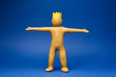 Photo of Plasticine figure with crown on head against blue background