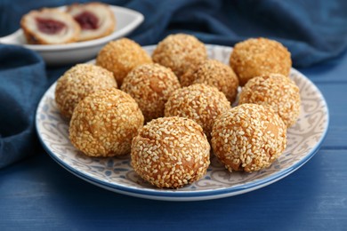 Photo of Delicious sesame balls on blue wooden table, closeup