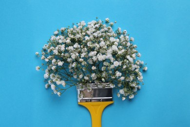 Creative composition with paint brush and gypsophila flowers on light blue background, top view