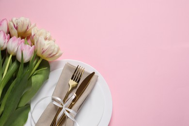 Photo of Stylish table setting with cutlery and tulips on pink background, flat lay. Space for text