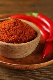 Paprika powder and fresh chili peppers on wooden table, closeup