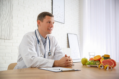 Nutritionist with clipboard at desk in office