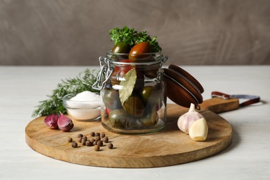 Pickling jar with fresh ripe tomatoes on white table