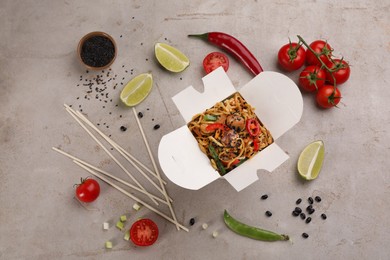 Box of wok noodles with vegetables and meat on light table, flat lay
