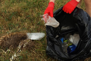 Woman in gloves with trash bag collecting garbage in nature, closeup