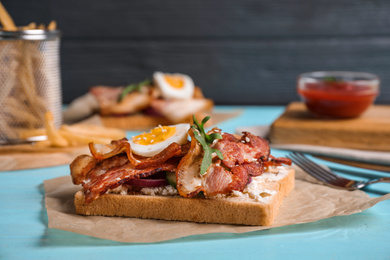 Delicious sandwich with bacon on blue table