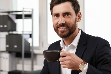Photo of Smiling bearded man with cup of drink indoors