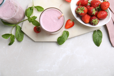 Tasty milk shake with strawberries on light grey marble table, flat lay. Space for text