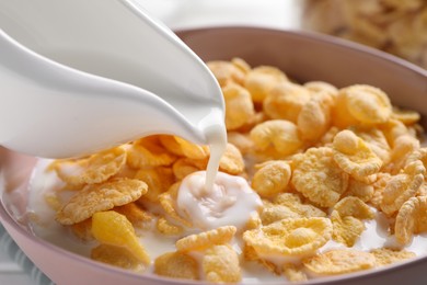 Pouring milk into bowl with cornflakes, closeup