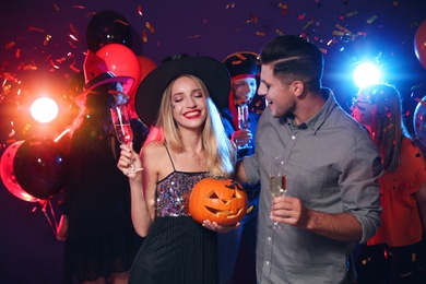 Happy couple enjoying Halloween party on dark background
