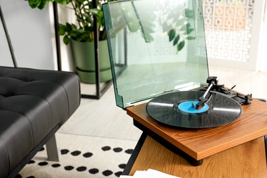 Photo of Vinyl record player on wooden table in living room