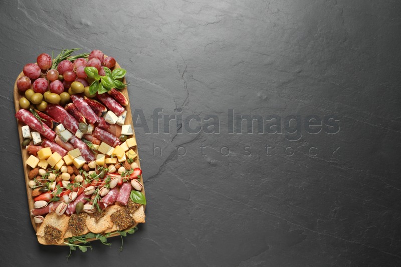 Different tasty appetizers on dark grey table, top view. Space for text