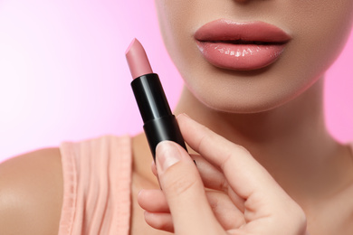 Woman with glossy lipstick on pink background, closeup