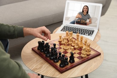 Man playing chess with partner via online video chat in living room, closeup