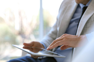 Businessman working with modern tablet in office, closeup