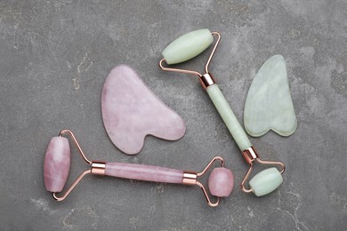 Photo of Different gua sha stones and face rollers on grey table, flat lay