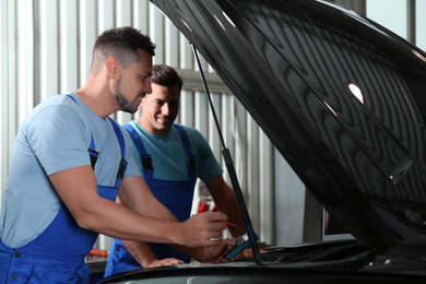Mechanics with laptop doing car diagnostic at automobile repair shop