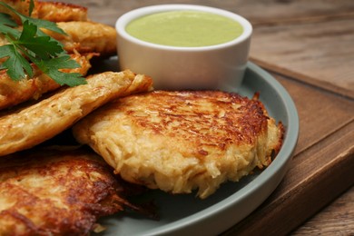 Photo of Tasty parsnip cutlets with sauce on wooden table, closeup