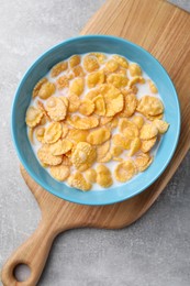 Photo of Bowl with tasty cornflakes and milk on light grey table, top view