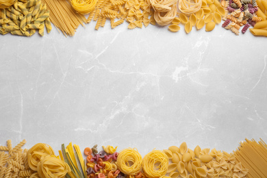 Different types of pasta on light grey marble table, flat lay. Space for text