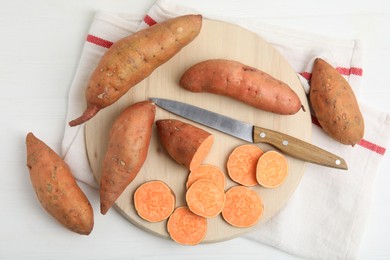 Whole and cut ripe sweet potatoes on white wooden table, flat lay