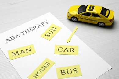 Taxi car model and paper sheet with phrase ABA Therapy on white wooden table