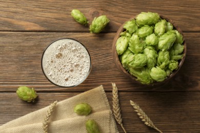 Photo of Glass of beer, fresh green hops and spikes on wooden table, flat lay