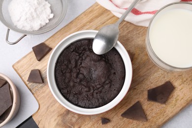 Photo of Tasty chocolate pie and ingredients on light grey table, flat lay. Microwave cake recipe