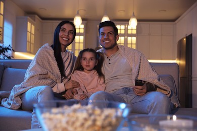 Family watching movie on sofa at night
