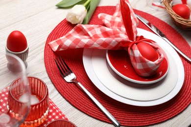 Photo of Festive table setting with bunny ears made of red egg and napkin. Easter celebration