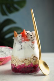Glass jar of granola with pitahaya, yogurt and strawberries on white table