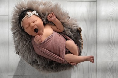 Photo of Cute newborn baby yawning in wicker basket, top view