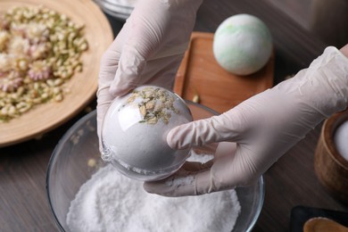 Photo of Woman in gloves making bath bomb at table, closeup