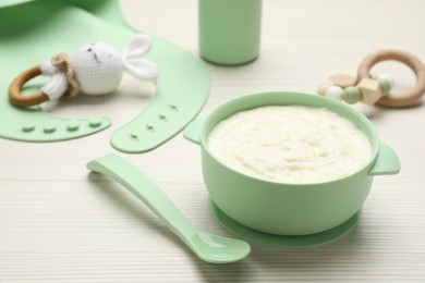 Photo of Plastic dishware with healthy baby food on white wooden table. Space for text
