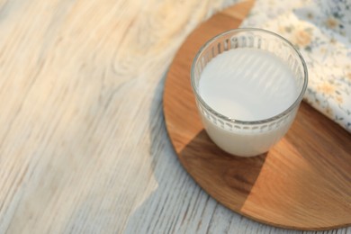 Glass of tasty fresh milk on white wooden table, above view. Space for text