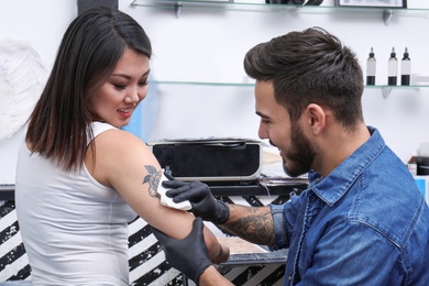 Photo of Professional artist making stylish tattoo in salon