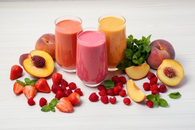 Photo of Fresh colorful fruit smoothies and ingredients on white wooden table