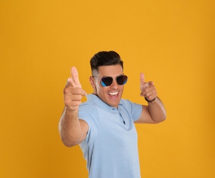 Excited man wearing sunglasses on yellow background
