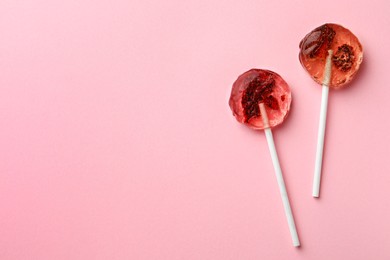 Sweet colorful lollipops with berries on pink background, flat lay. Space for text
