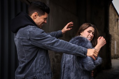 Criminal attacking young woman in alley. Self defense concept